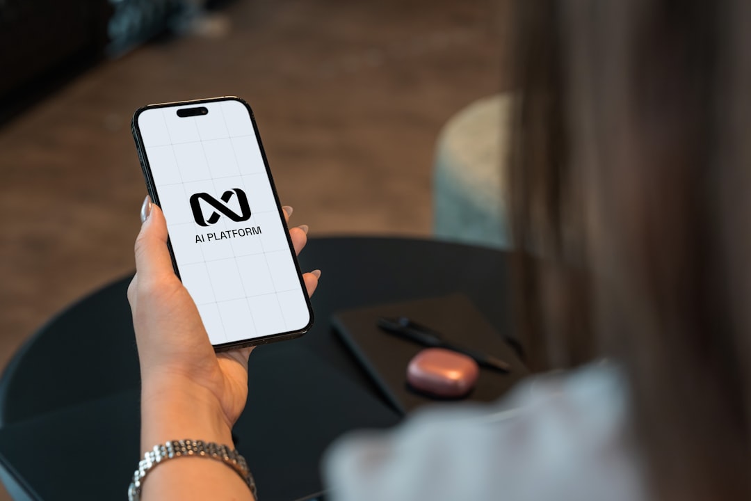 Person holding a smartphone with a logo on screen.