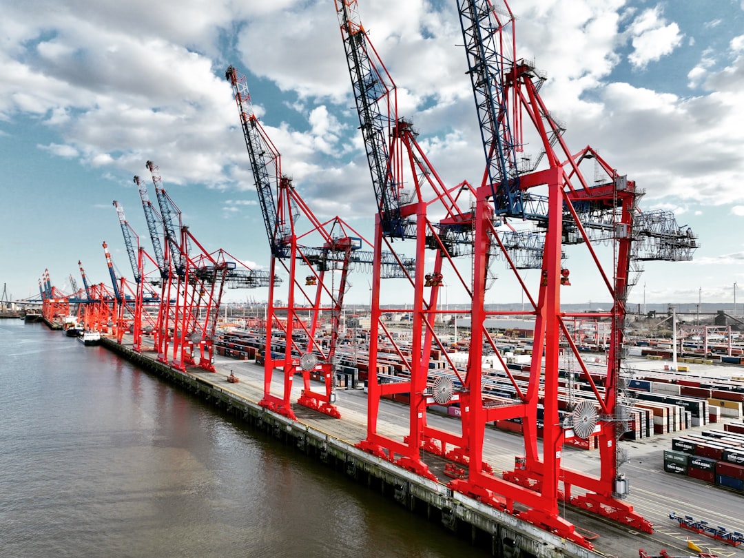 Row of red cranes at a busy shipping port.