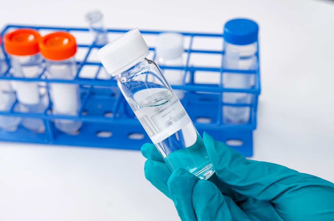 Hand in glove holding test tube with liquid