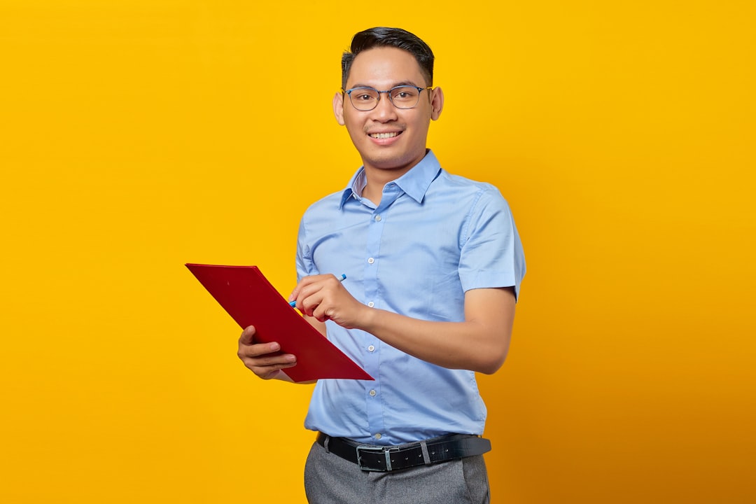 a man in a blue shirt is holding a red folder