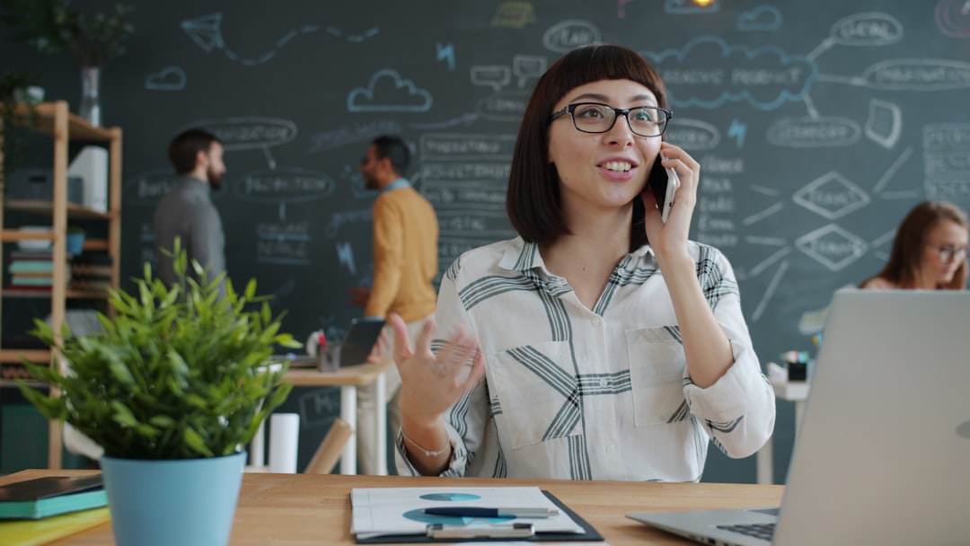 Woman talking on phone in modern office with chalkboard wall.