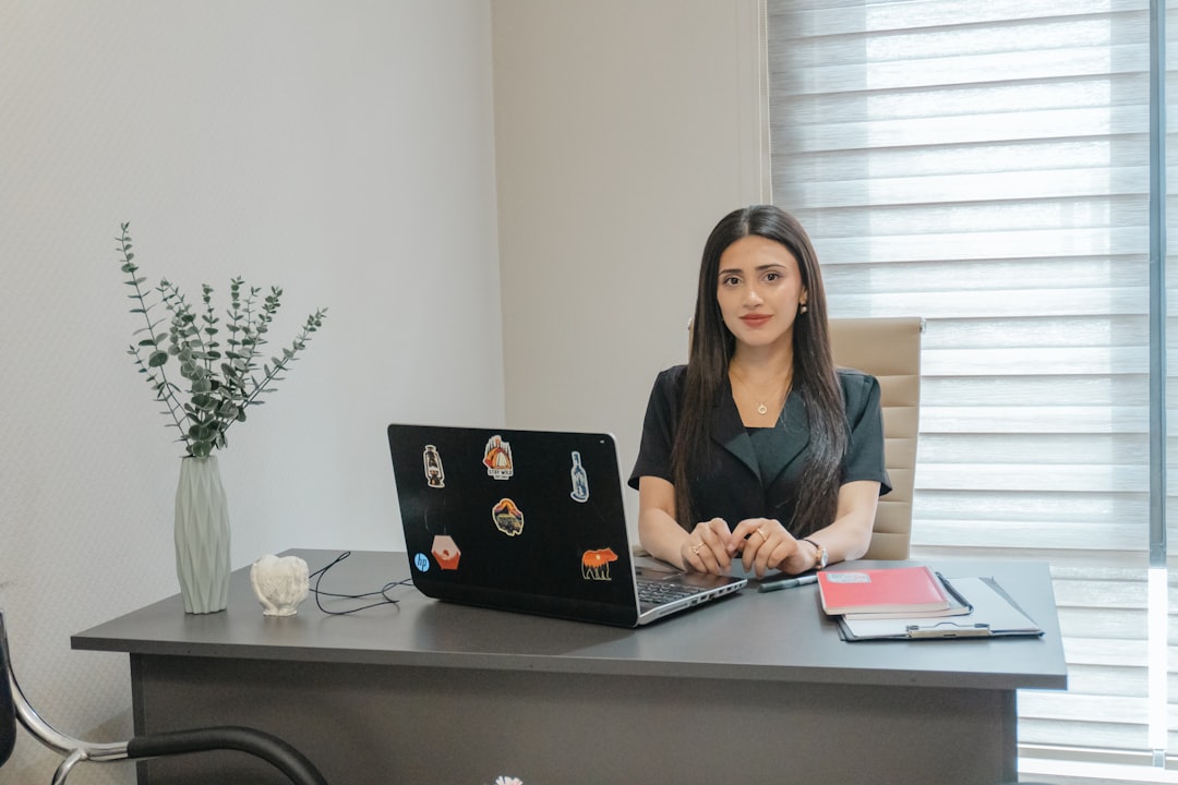 A woman sits at a desk with a laptop.