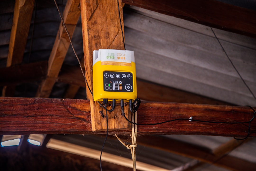 Yellow device mounted on wooden beam with wires