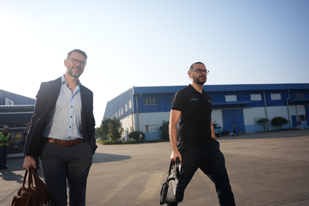 Two men walking with briefcases outside industrial buildings