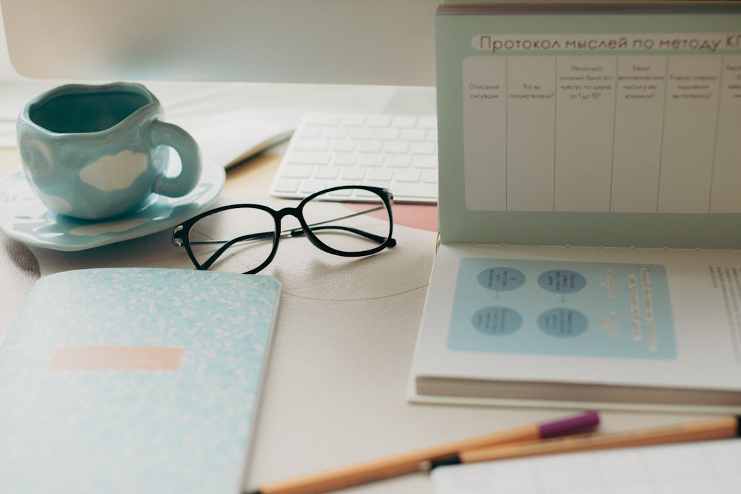 Desk with glasses, coffee cup, and notebooks.