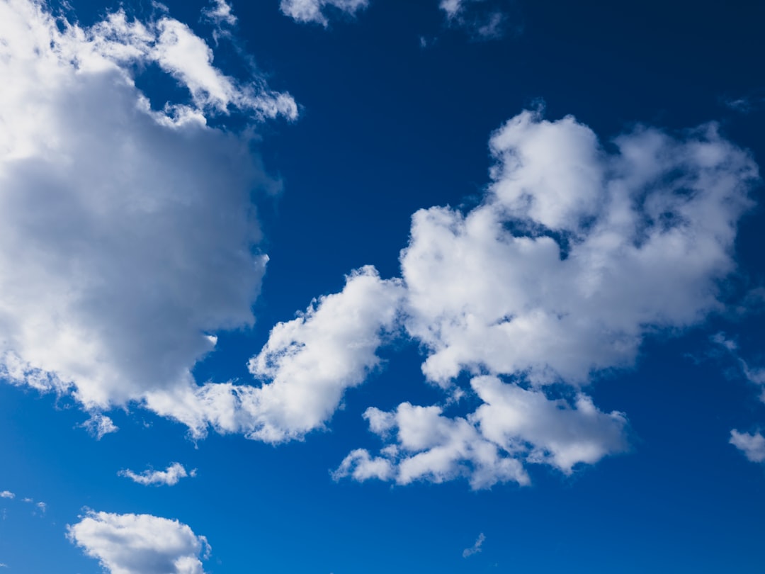 Fluffy white clouds drift across a vibrant blue sky.