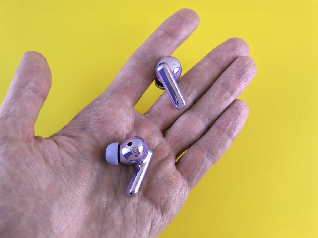 A hand holding a pair of silver ear buds