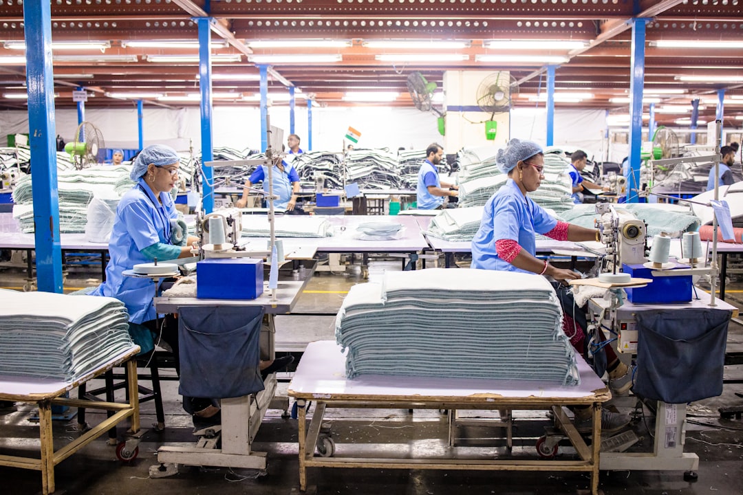 Workers sew textiles in a large factory setting.