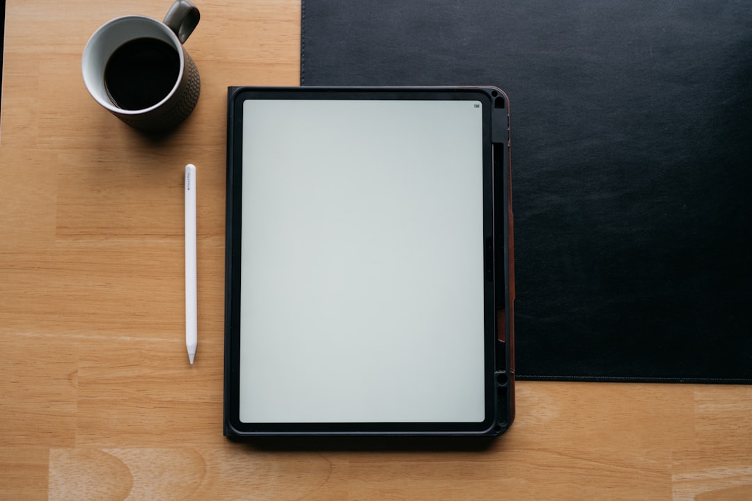 Tablet, pen, and coffee on a wooden desk.