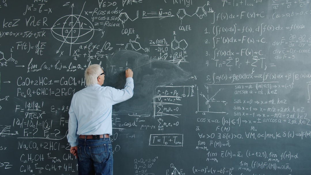 Professor writing complex mathematical equations on a chalkboard.