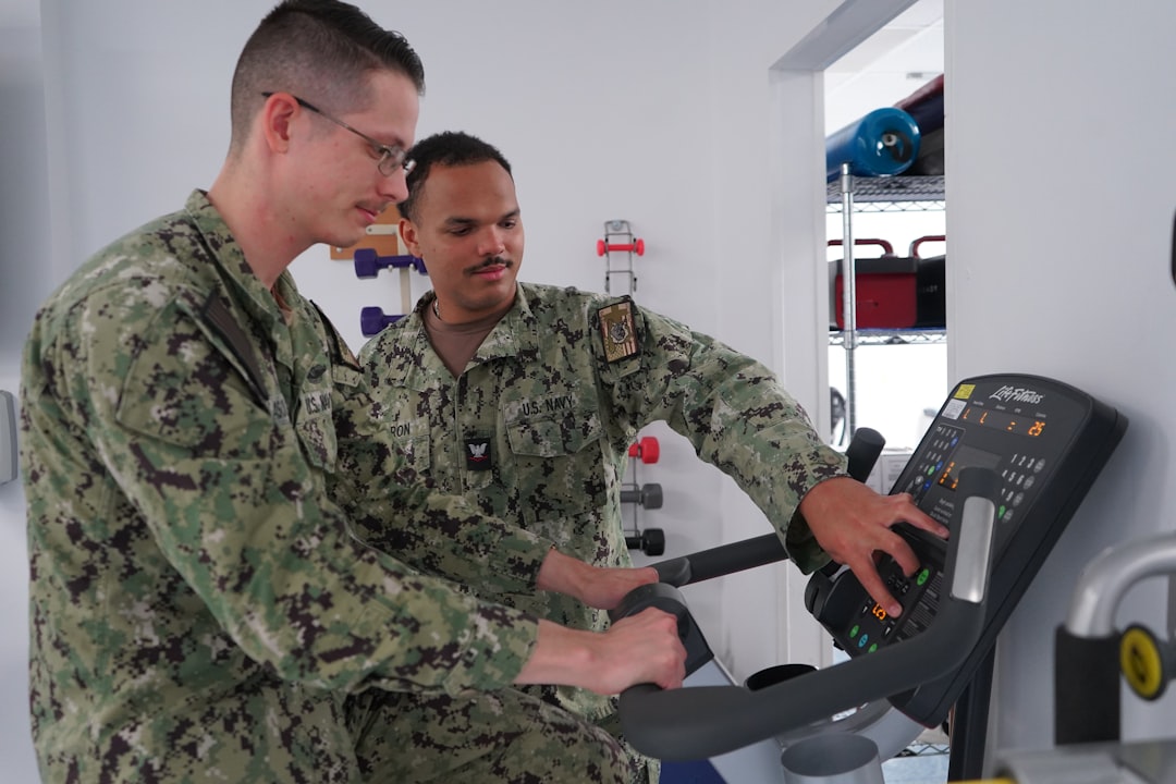 Two men in military uniforms on exercise bike.