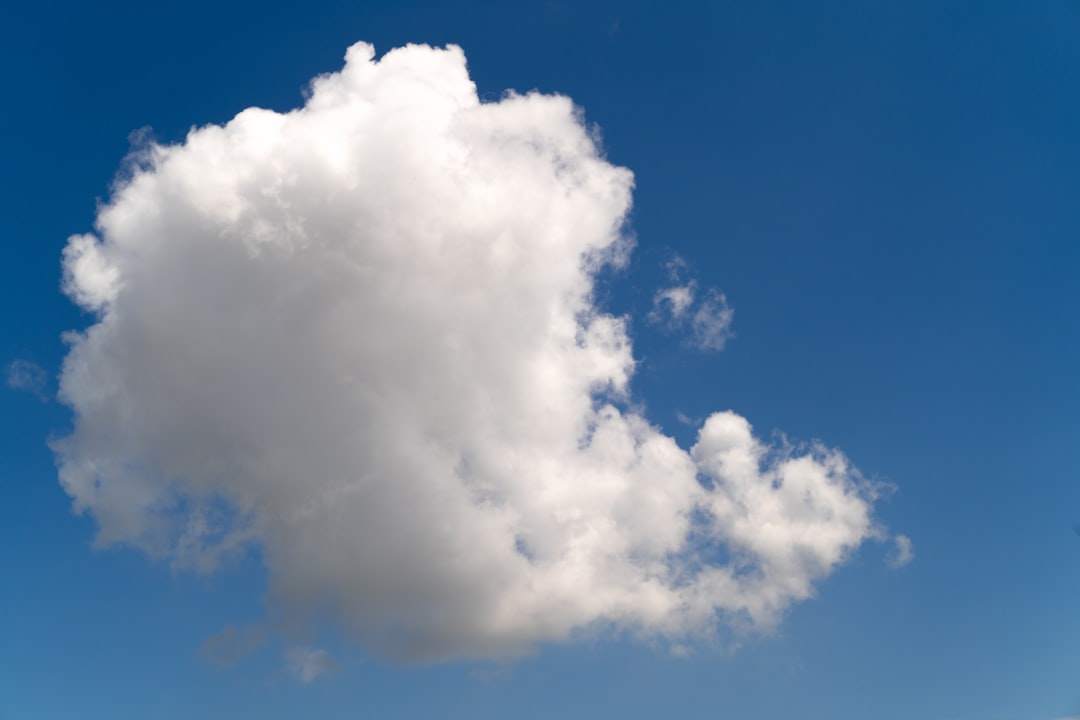 A single white cloud floats in a clear blue sky