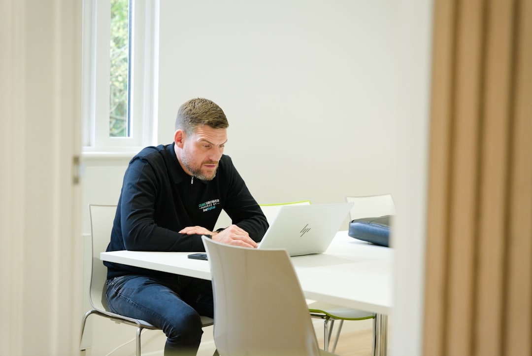 Man working on laptop at a white table.
