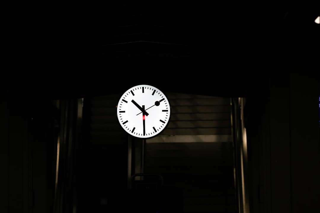 A white clock face with black hands on dark background