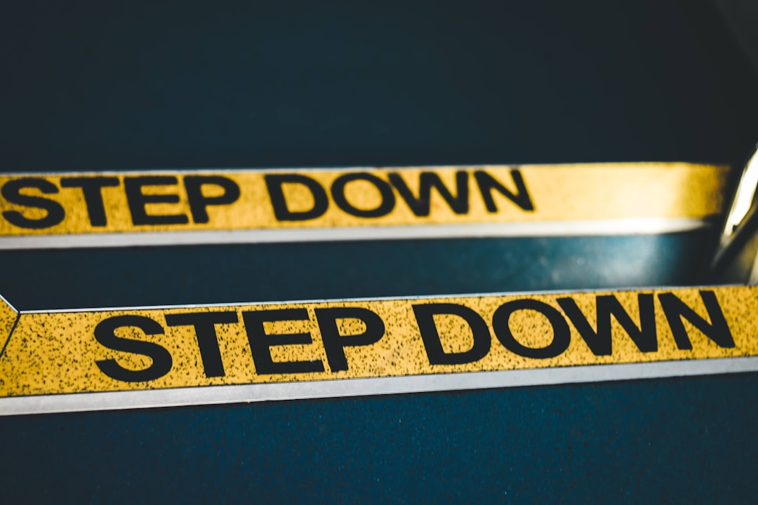 a close up of a pair of scissors near a step down sign