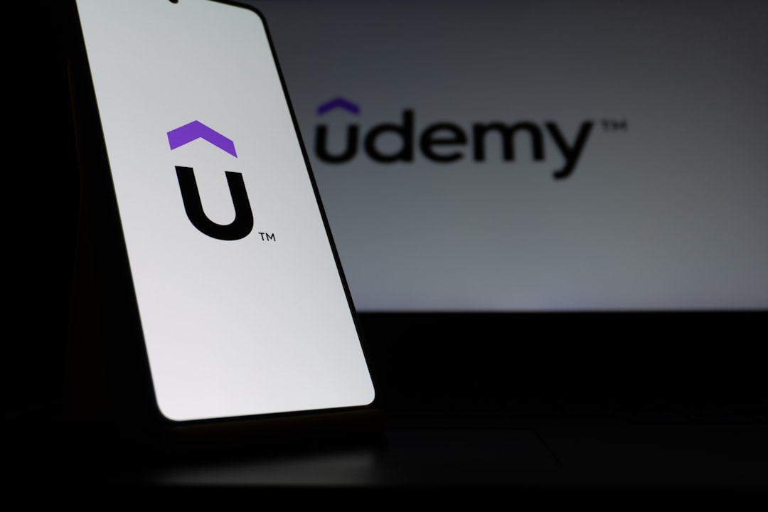 Udemy logo on a smartphone screen and laptop.