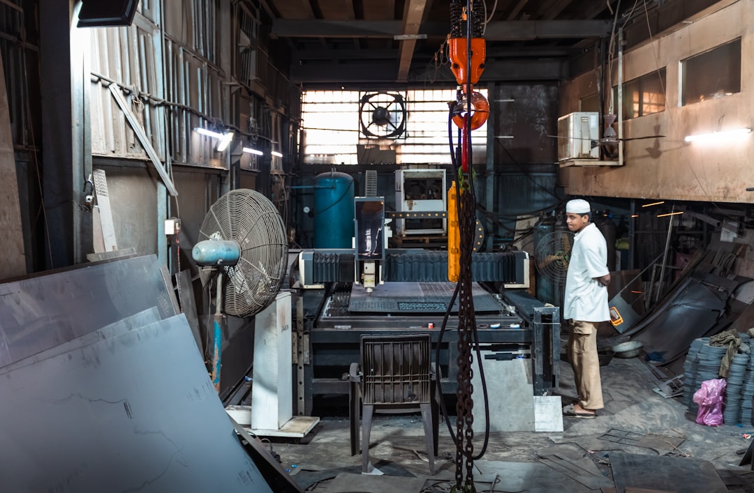 Man standing in a cluttered industrial workshop.
