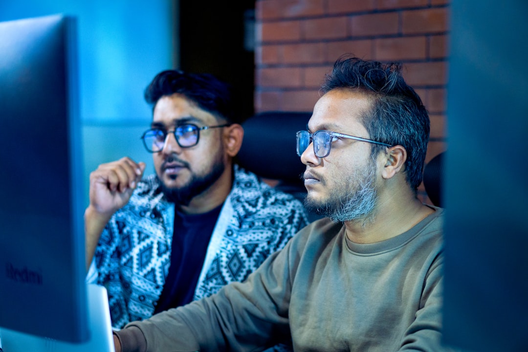 Two men looking intently at a computer screen.