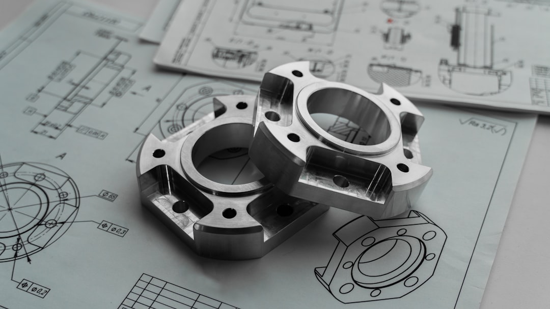 Two metal mechanical parts on engineering blueprints