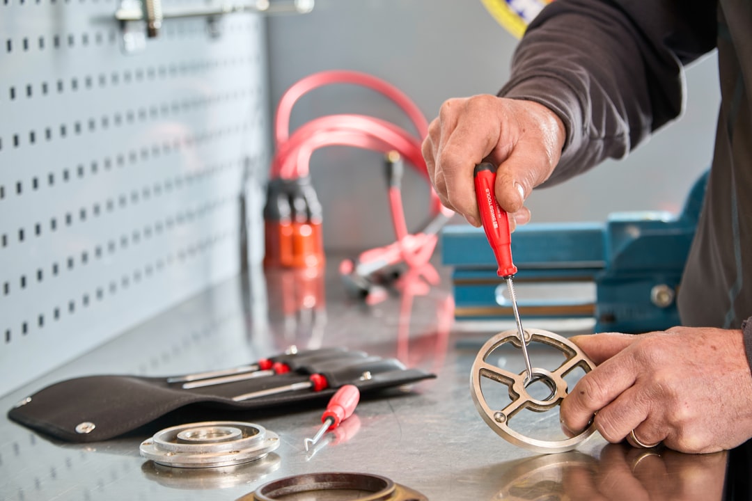 Mechanic working on a metal part with tools.