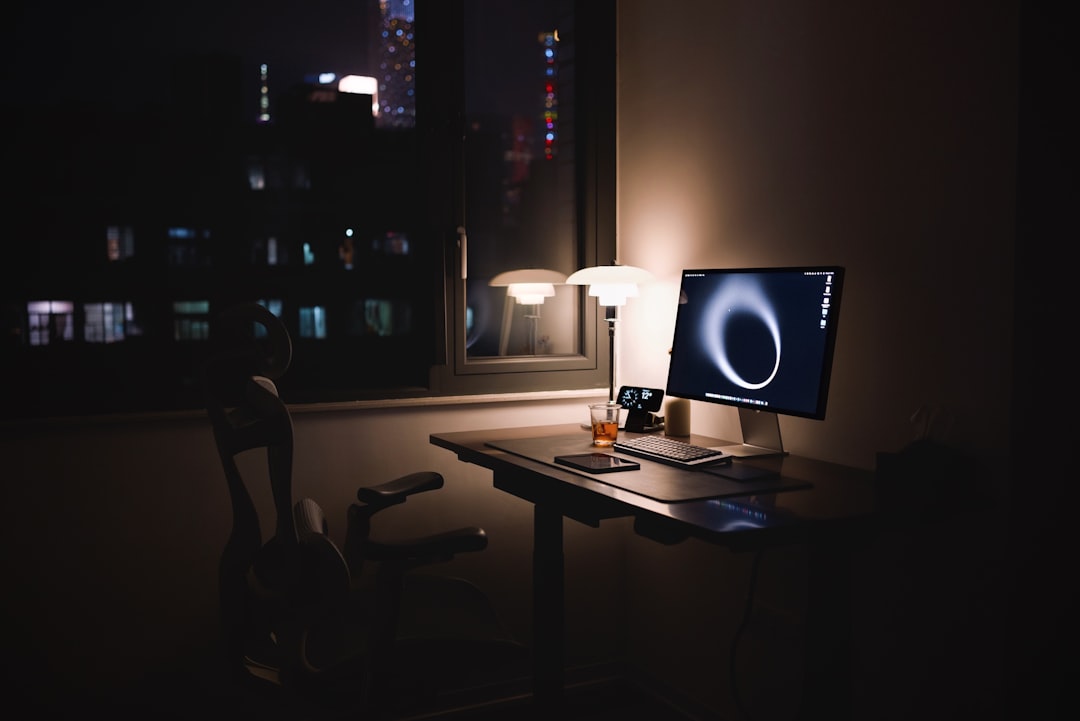 Desk with computer and lamp at night